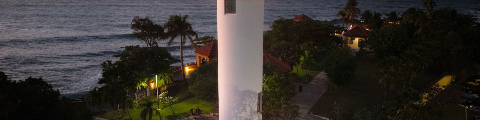 A lighthouse at sunset with the ocean in the background.