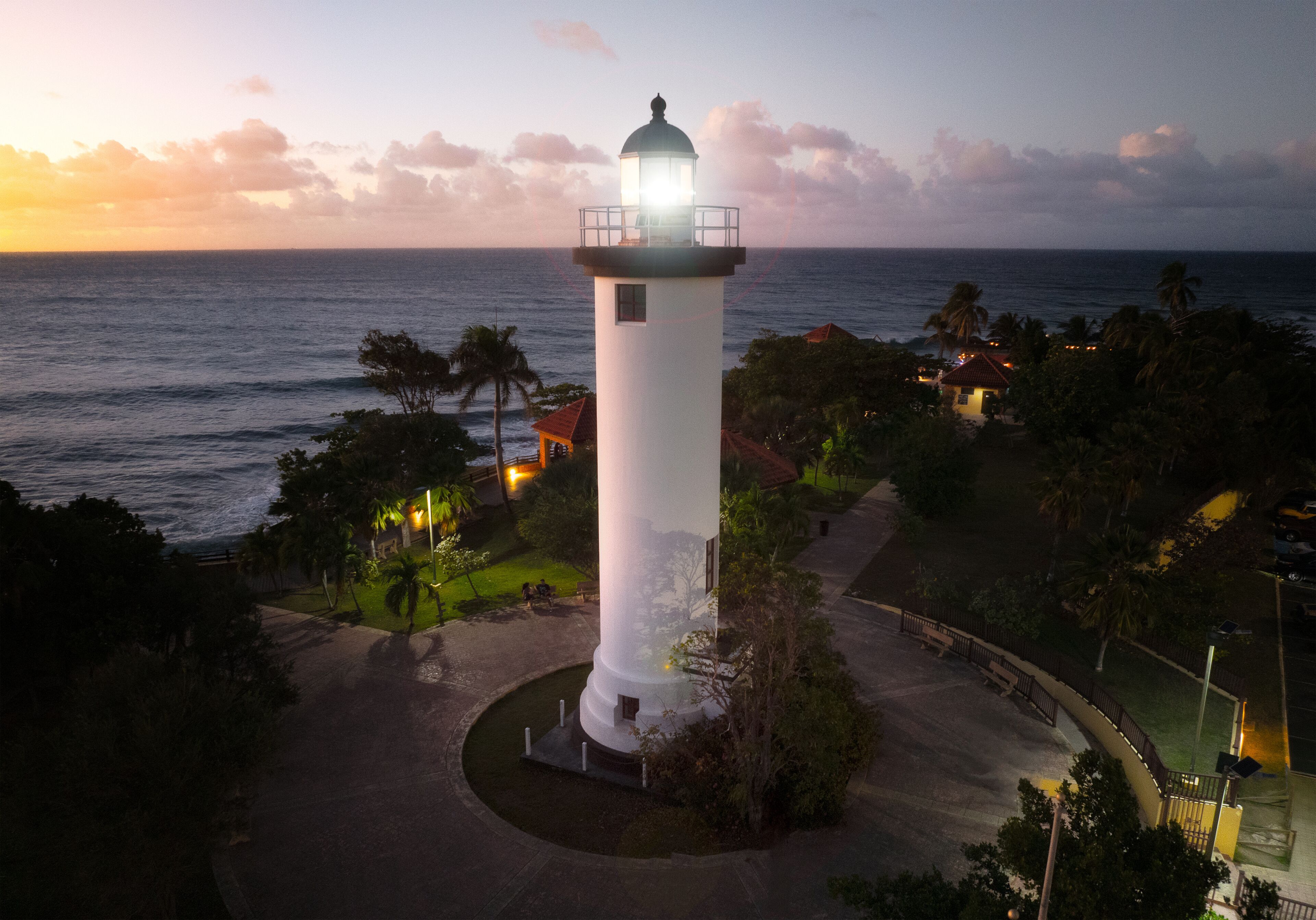 A lighthouse at sunset with the ocean in the background.