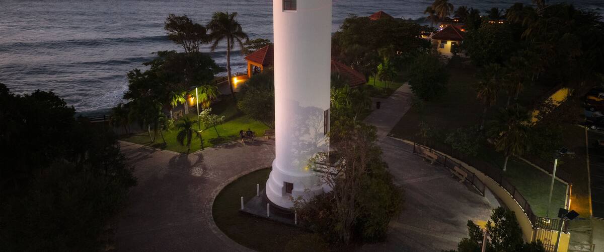 A lighthouse at sunset with the ocean in the background.