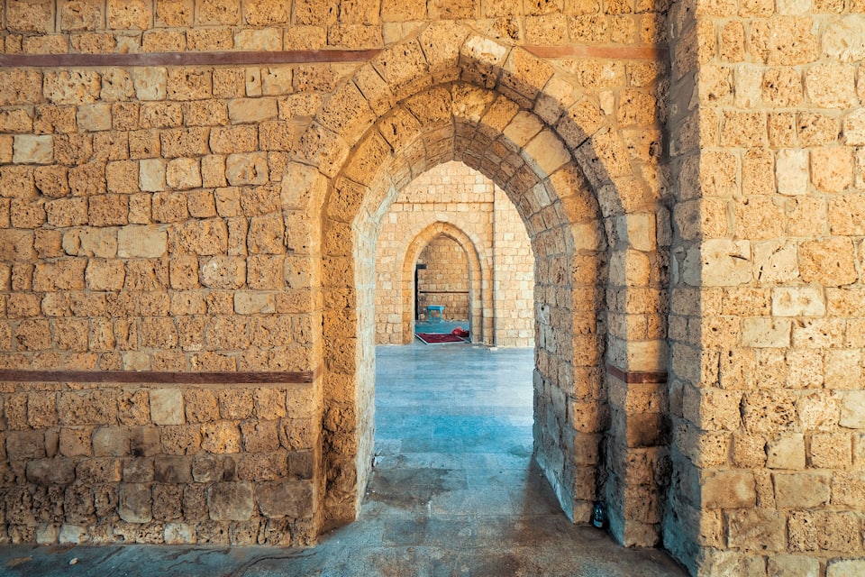 An arched stone corridor with a bench at the end.