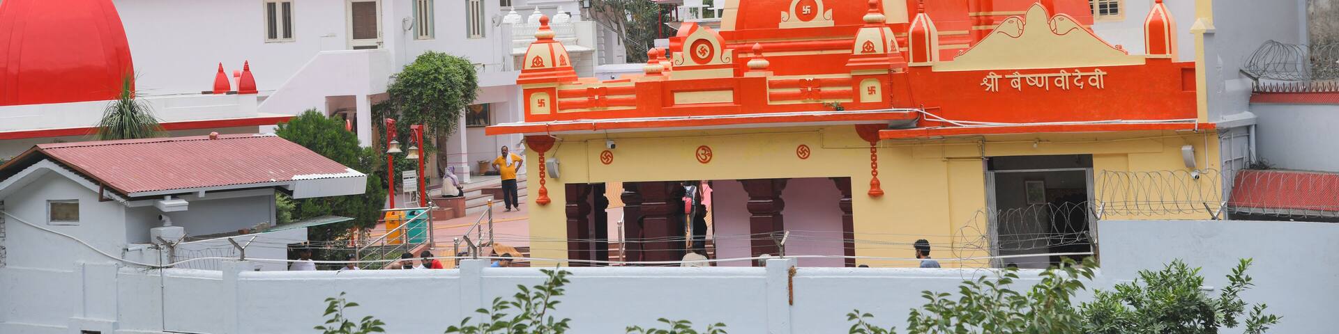 Kainchi Dham Temple, Uttarakhand, where a river flows next to a sacred temple that is surrounded by hills and trees.