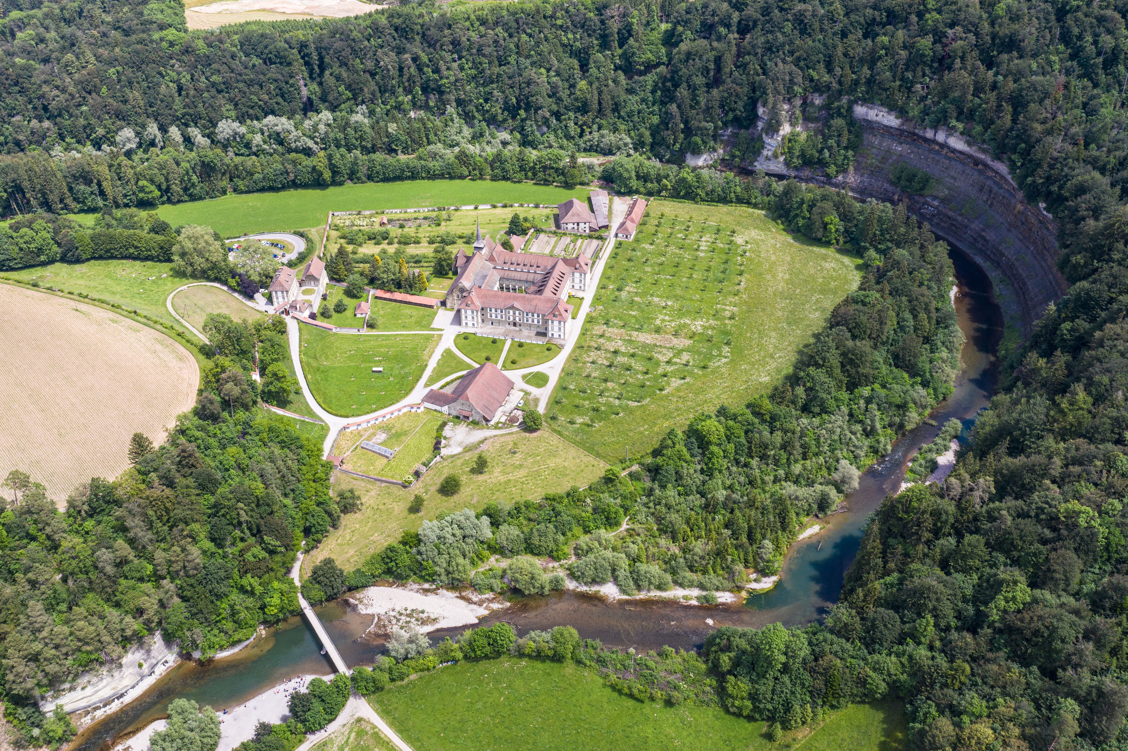 An aerial view of a castle surrounded by lush greenery and a river.