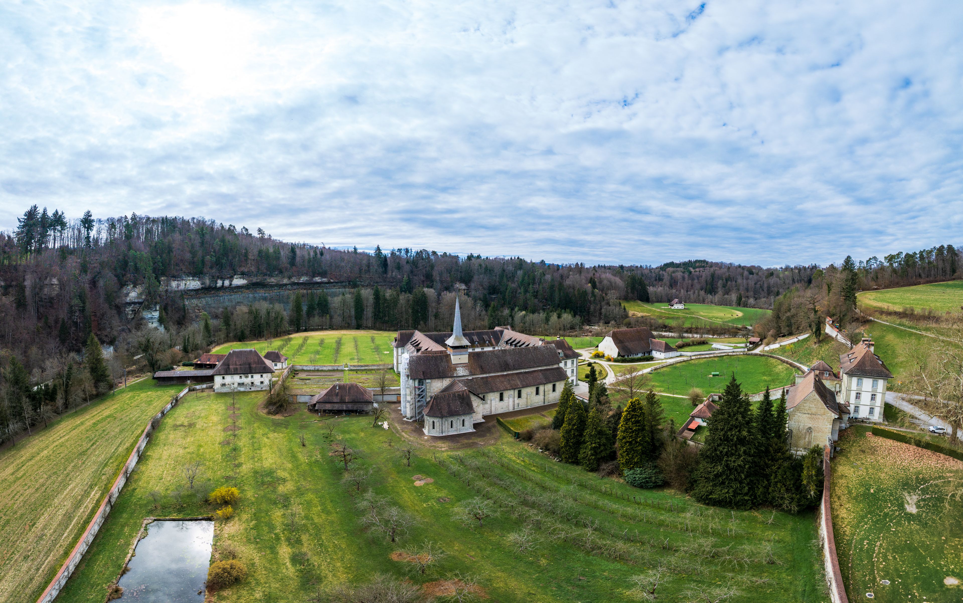 A rural landscape with a church, several houses, and a river.