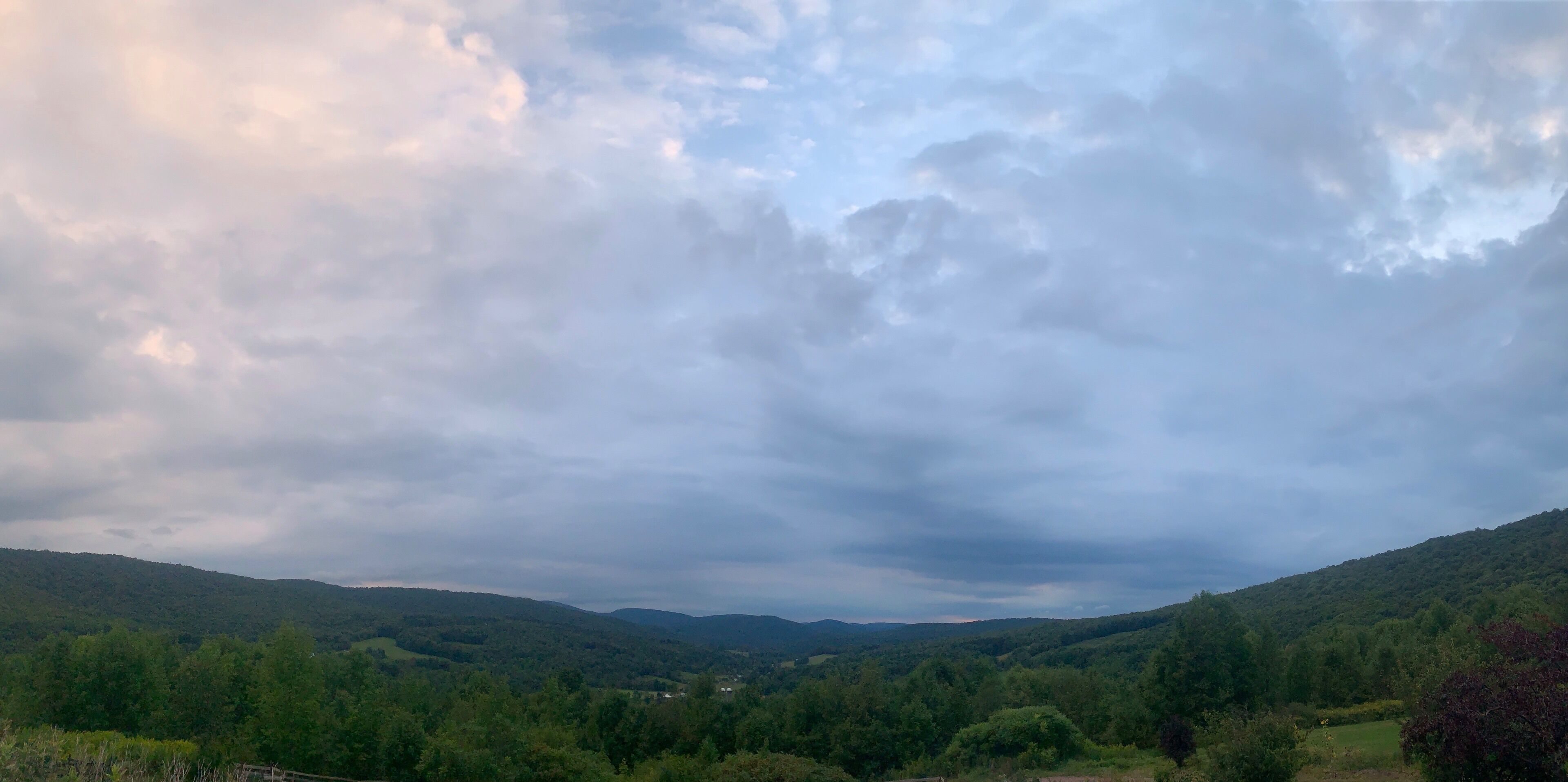 A valley with rolling hills and a cloudy sky.
