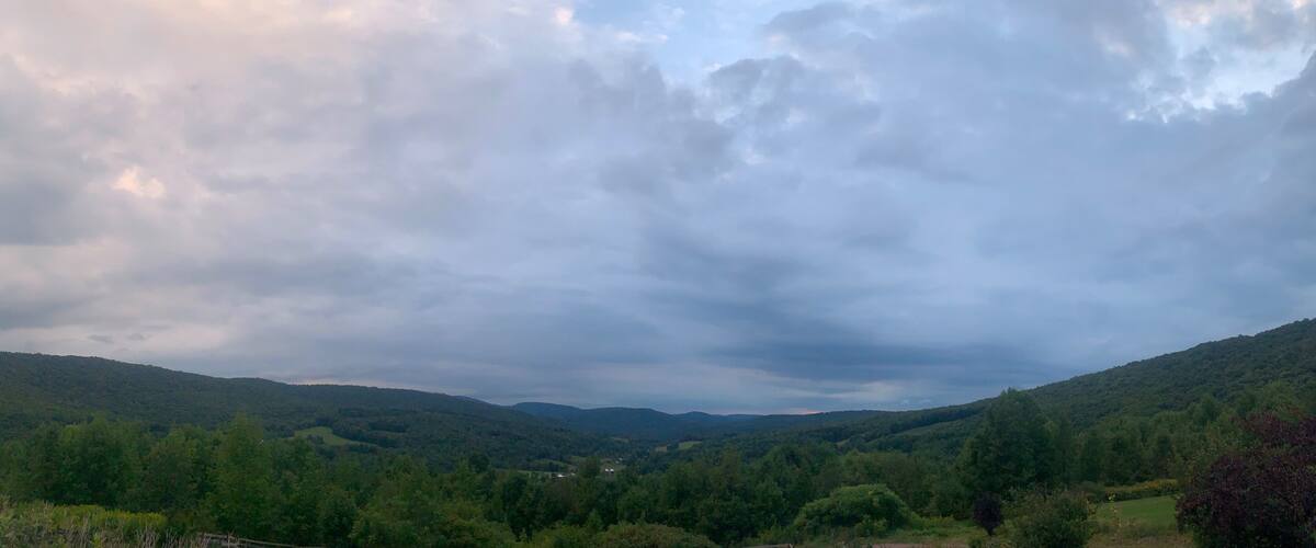 A valley with rolling hills and a cloudy sky.