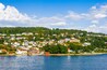 A coastal town with houses on a hillside and a body of water in the foreground.