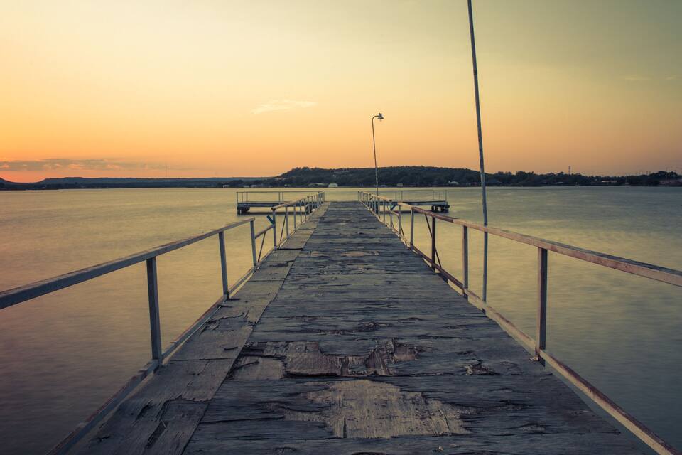 Un muelle de madera se adentra en aguas tranquilas al atardecer.
