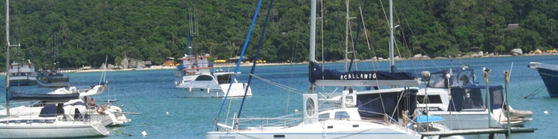 A marina with several sailboats docked, surrounded by lush green hills.