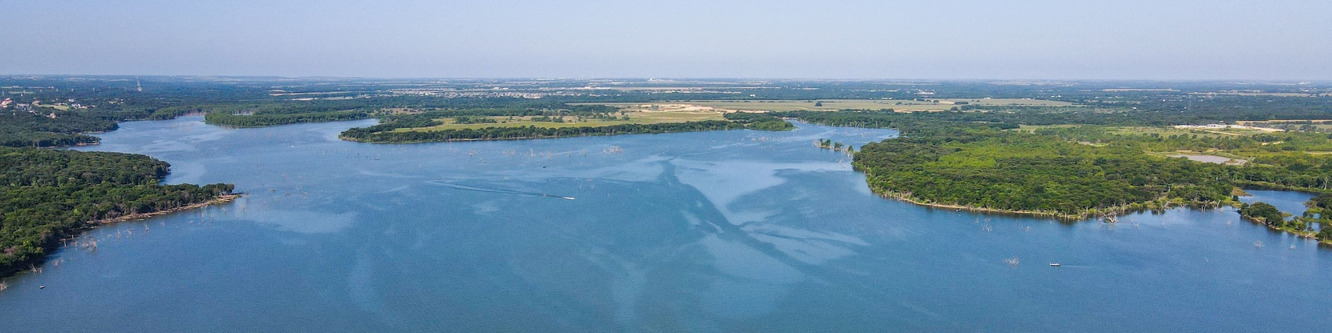 A large river winding through a green landscape with islands and a distant city skyline.
