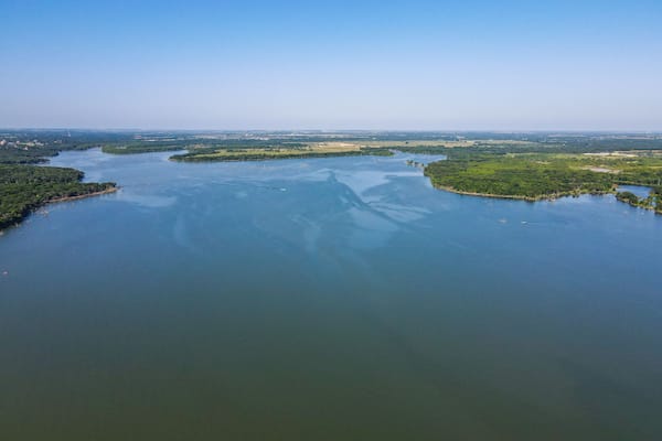 A large river winding through a green landscape with islands and a distant city skyline.