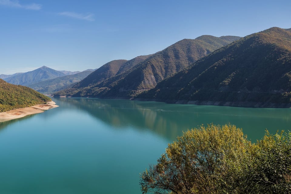 A calm lake surrounded by forested mountains.