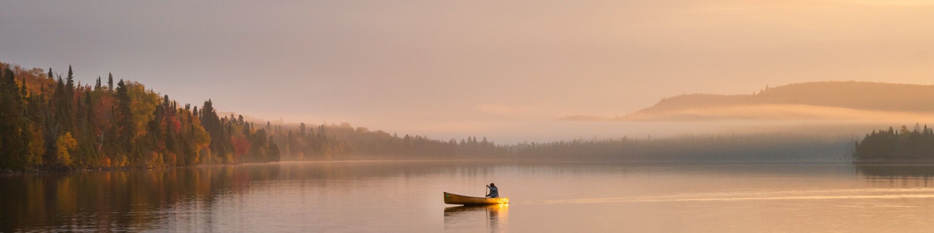 People are boating on Caribou Lake on a fogy morning