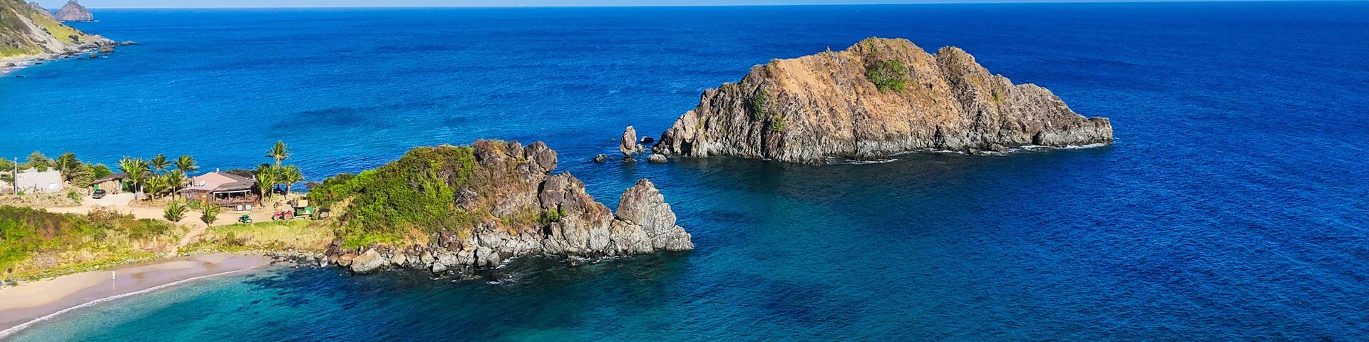 Vista aérea da Ilha da Conceição em Fernando de Noronha, com mar azul cristalino, formações rochosas e vegetação tropical preservada