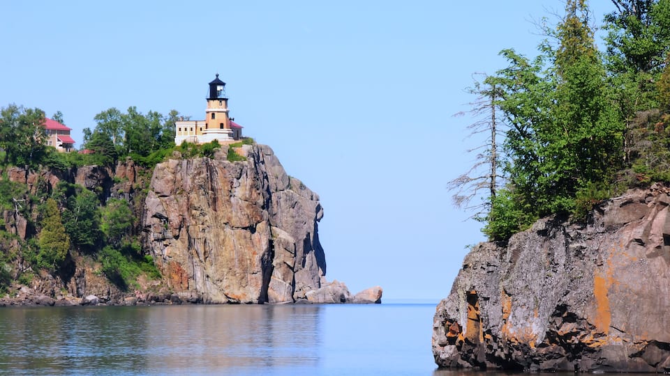 A lighthouse on a rocky cliff by the water.