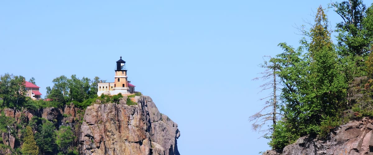 A lighthouse on a rocky cliff by the water.