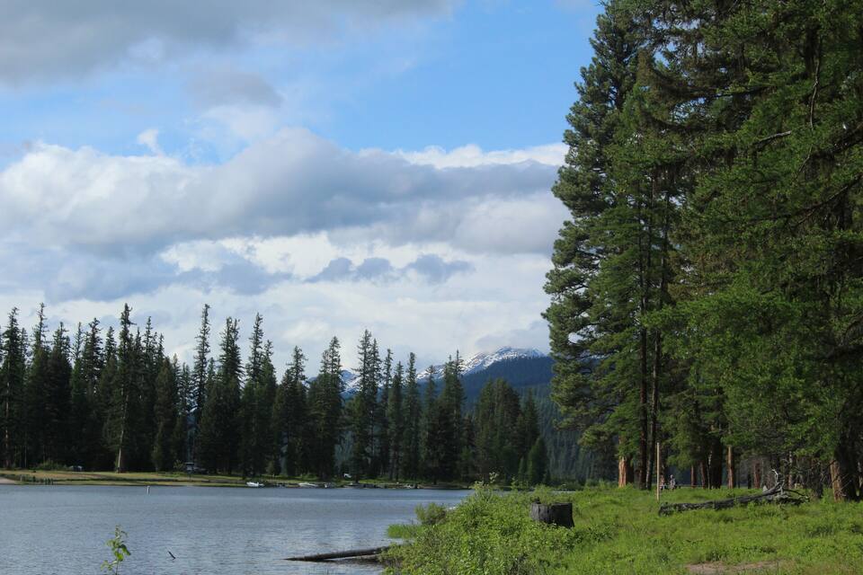 A lake surrounded by dense forests and mountains in the background.