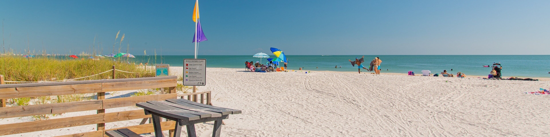 A beach with a wooden boardwalk, beach chairs, and umbrellas.