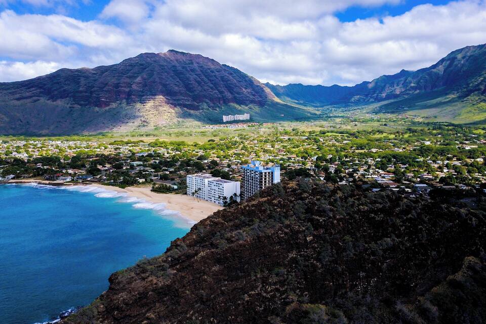 Une ville côtière dotée d’une plage, d’une grande montagne et d’un hôtel.