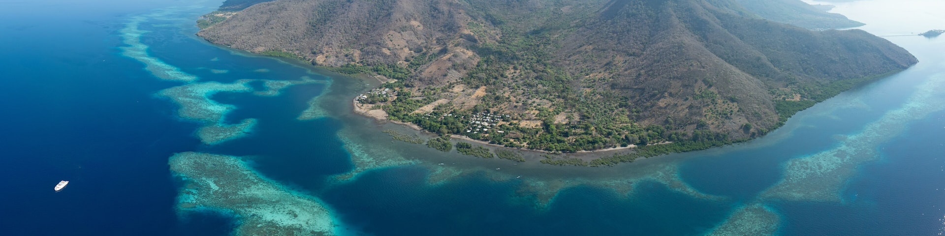 A beautiful and healthy coral reef surrounds a volcanic island off the coast of Flores, Indonesia. This area, in the Lesser Sunda Islands, is known for its high marine biodiversity.