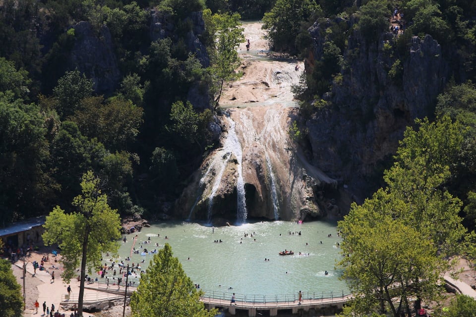 Una cascata che si getta in una vasca circondata da una fitta foresta.