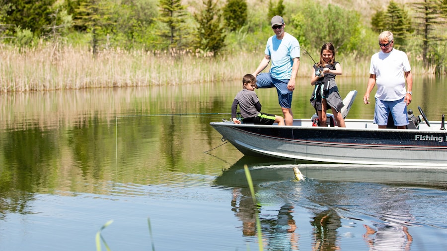 Young girl reeling in a fish on a boat with her family