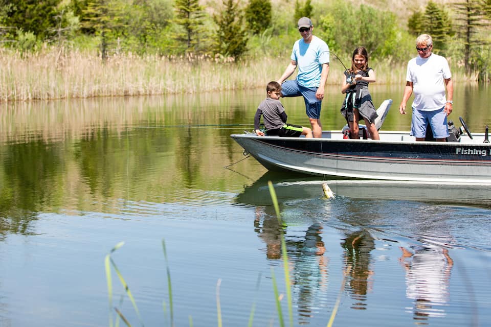 A calm lake with a boat named "Fishing" and people on it.