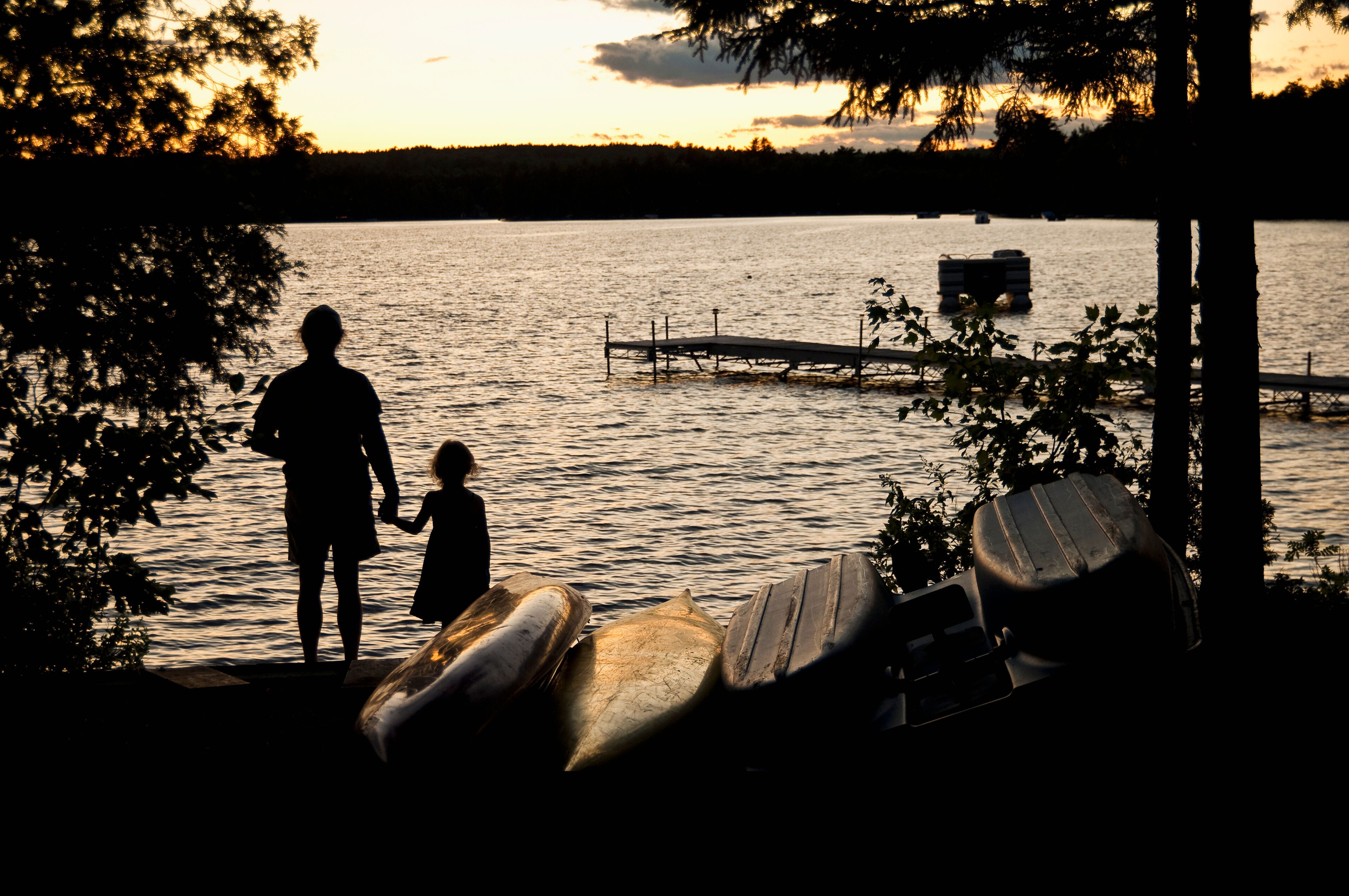 Father and daughter watch a sunset on beech hill pond;Otis maine united states of america