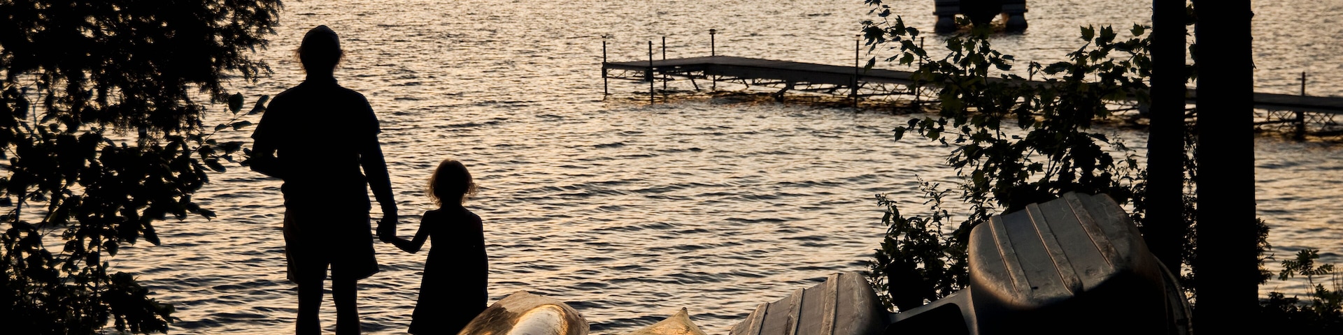 Father and daughter watch a sunset on beech hill pond;Otis maine united states of america