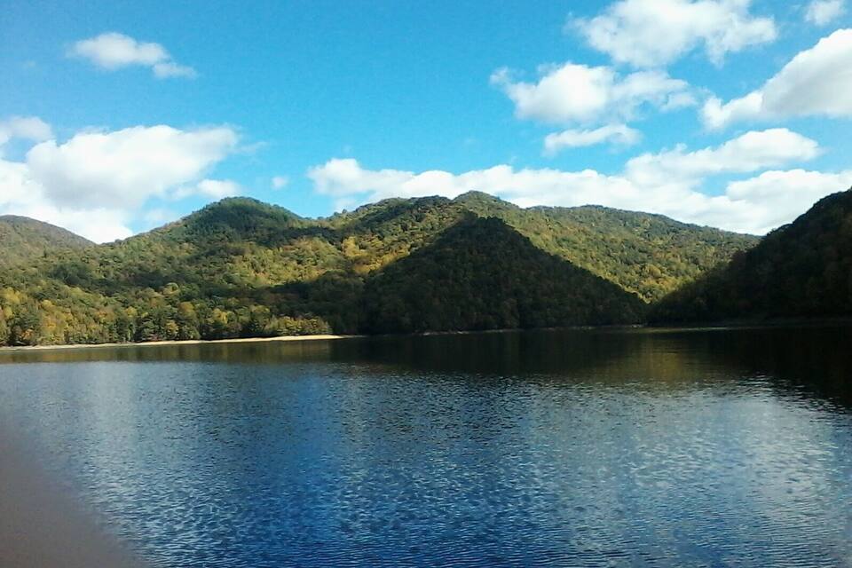 Un lac paisible, entouré de collines boisées, sous un ciel dégagé.