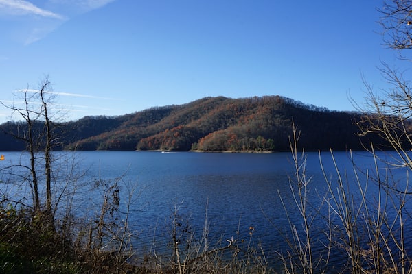 A calm lake surrounded by hills with autumn foliage.