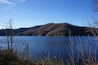 A calm lake surrounded by hills with autumn foliage.