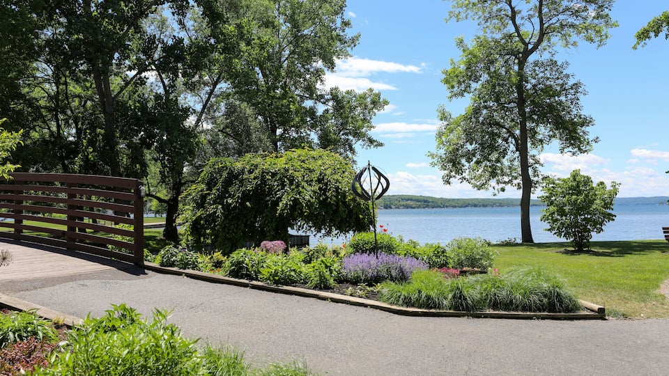 A park with a wooden bench, a metal sculpture, and a lake in the background.