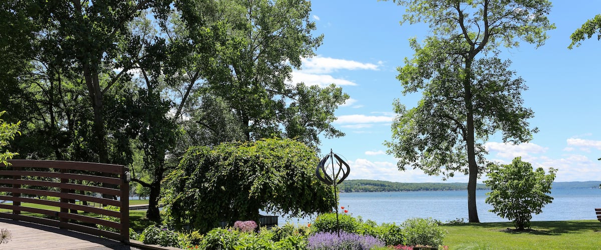A park with a wooden bench, a metal sculpture, and a lake in the background.