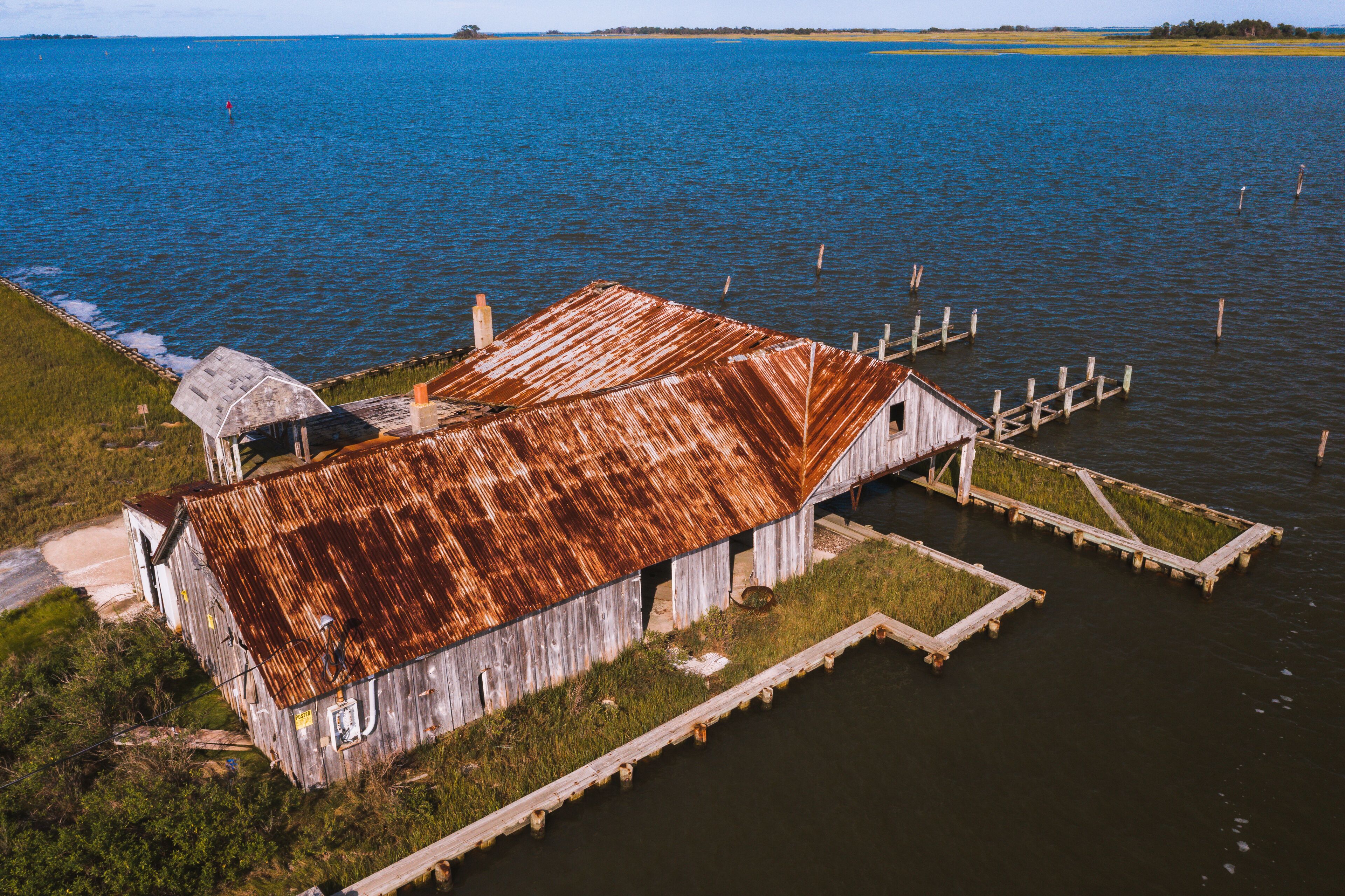 This is an aerial of an abandoned oyster house along the shores of Chincoteague Bay on George Island Landing, a declined oyster, clam, and crab fishing village in Maryland.