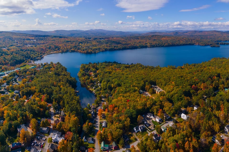 A lake surrounded by autumn-colored trees and a residential area.