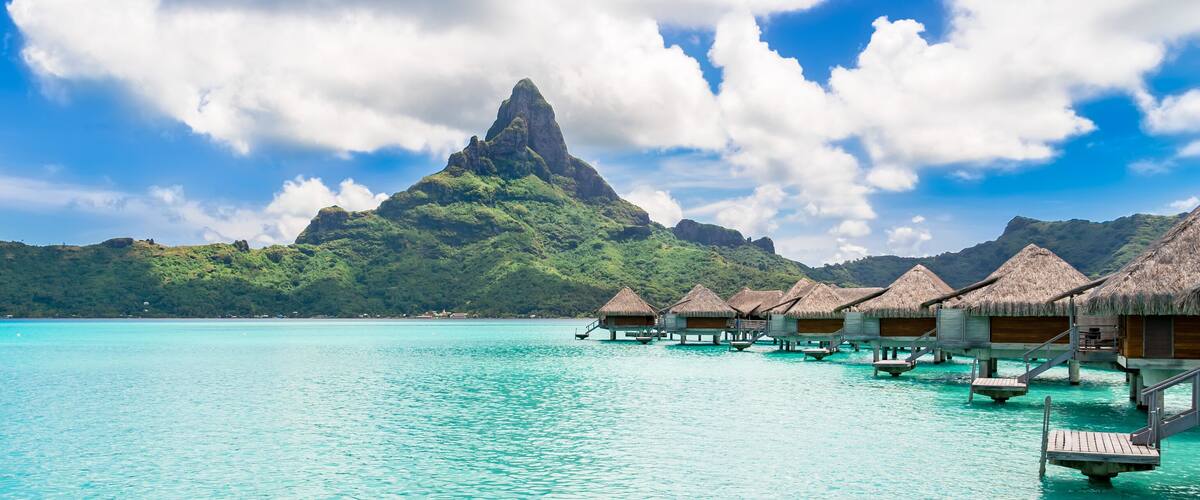 Overwater bungalows, turquoise waters, and a prominent mountain peak.