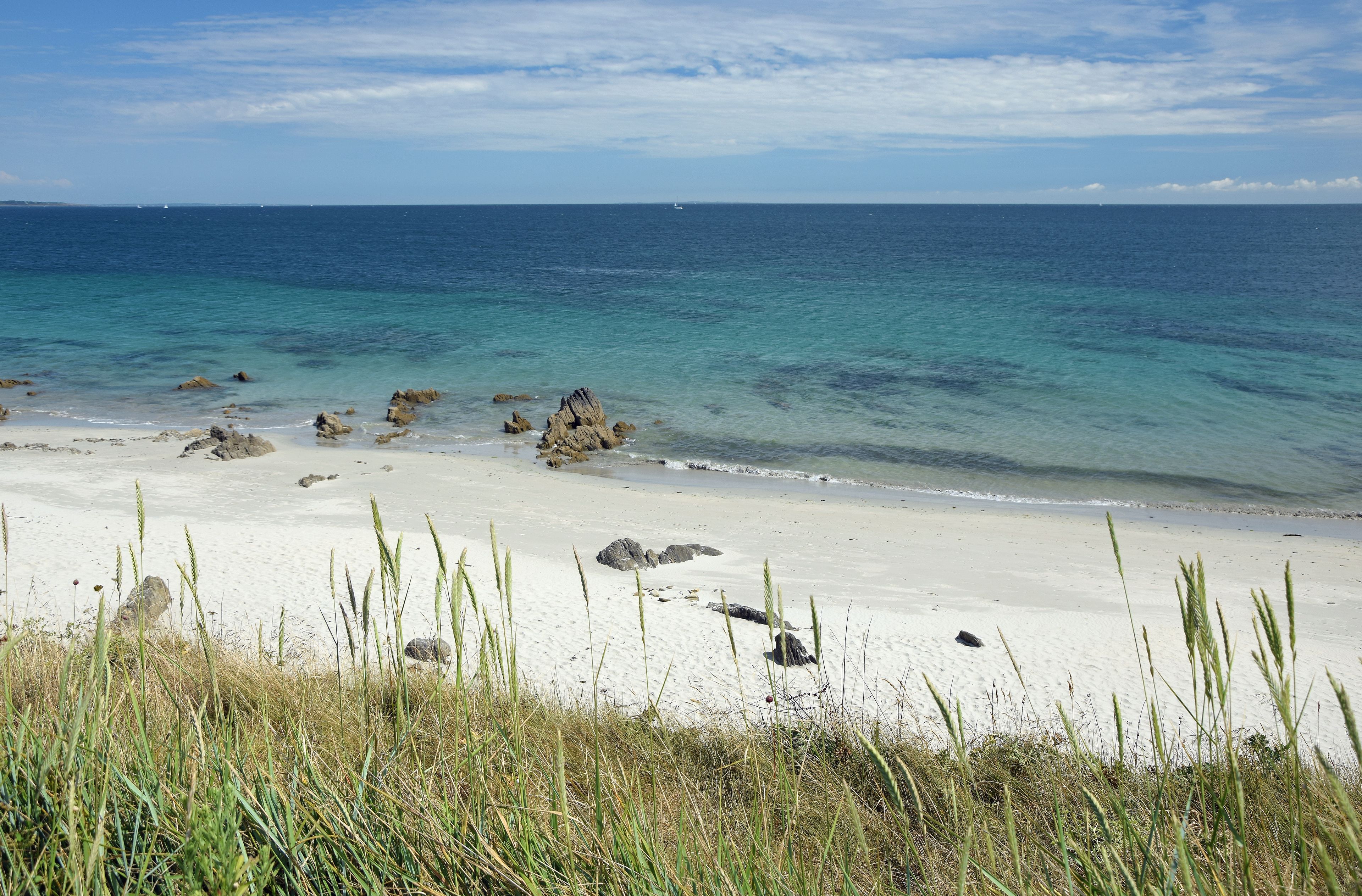 En strand med hvidt sand, krystalklart turkis vand og klippeformationer.