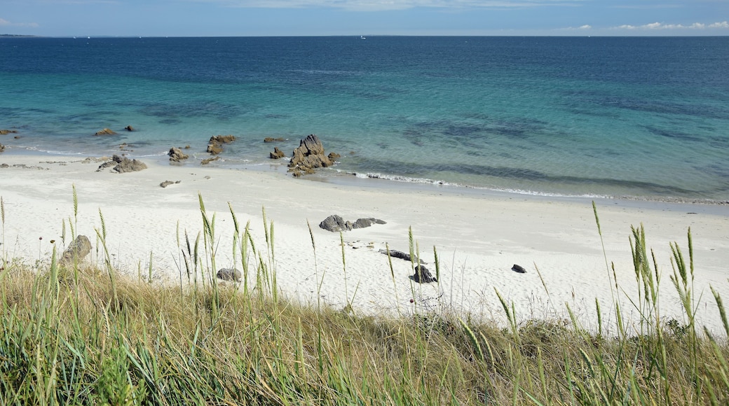 En strand med hvidt sand, krystalklart turkis vand og klippeformationer.