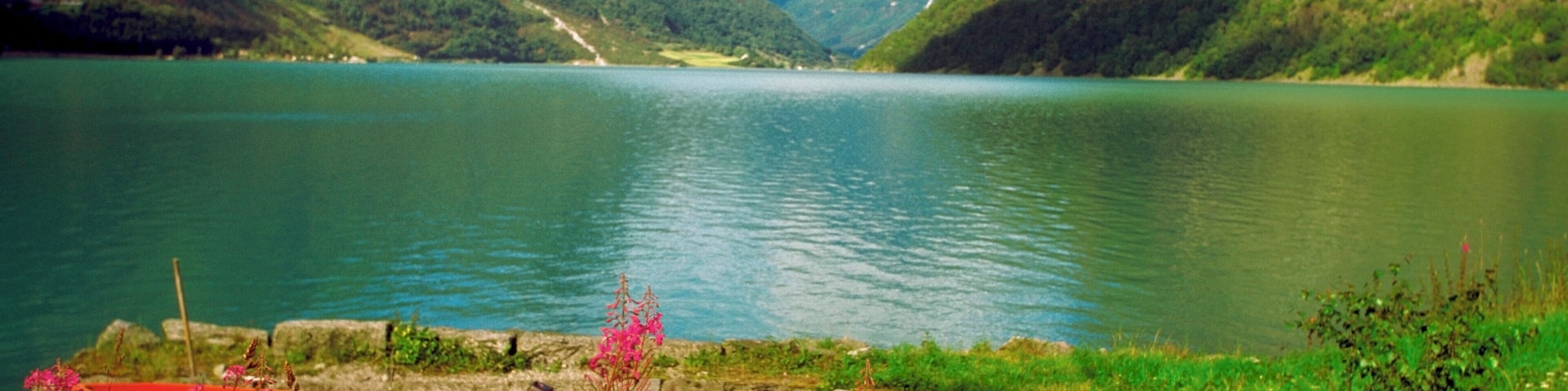 A lake surrounded by mountains with two boats docked at a stone pier.