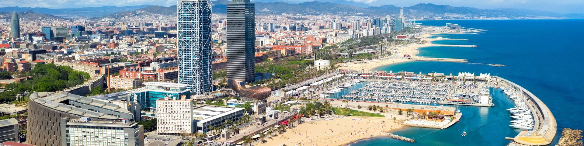 A coastal cityscape with a prominent beach, a marina, and high-rise buildings.