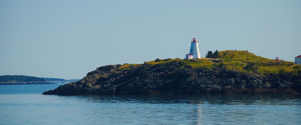 A lighthouse on a rocky island with calm water.