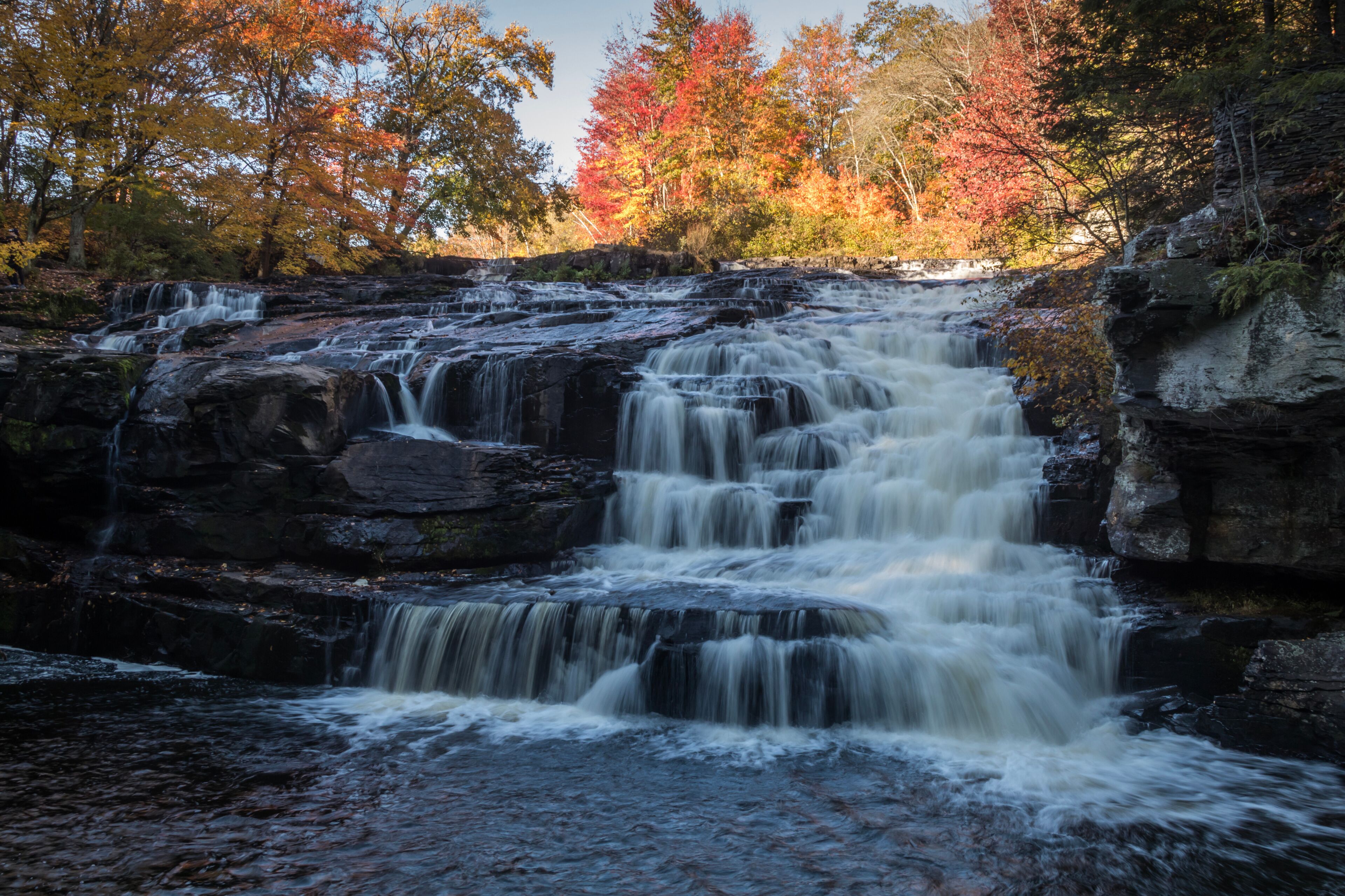 Peak fall foliage surrounds beautiful cascading lower Shohola Falls on an Autumn morning in the Pennsylvania Poconos