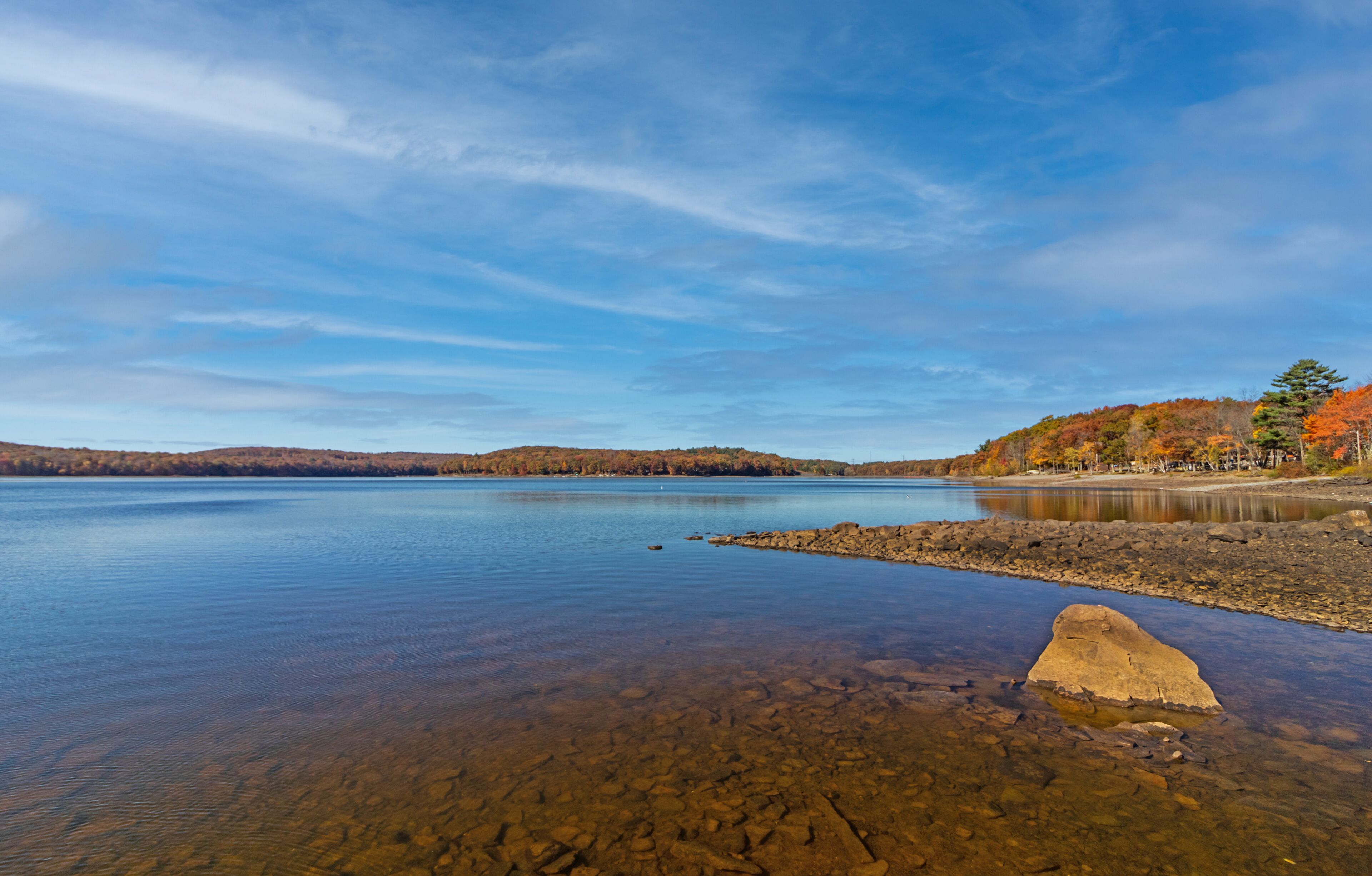 Lake Wallenpaupack in Poconos PA on a bright fall day lined with trees in vivid and beautiful foliage