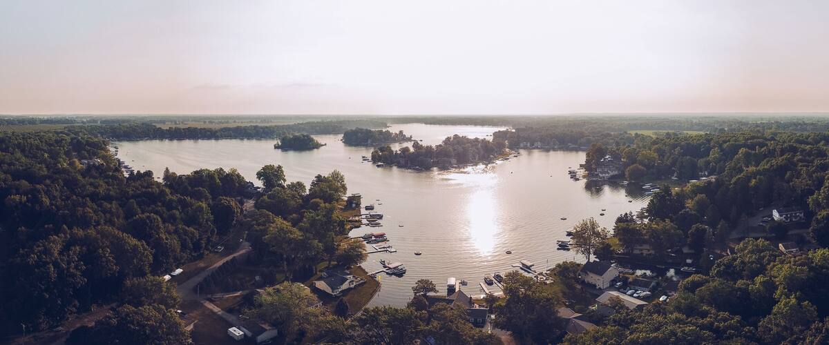 A lake surrounded by dense forest and small buildings.