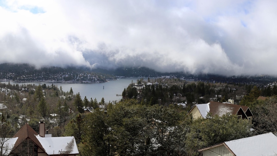 A mountainous landscape with a lake, houses, and dense forest.