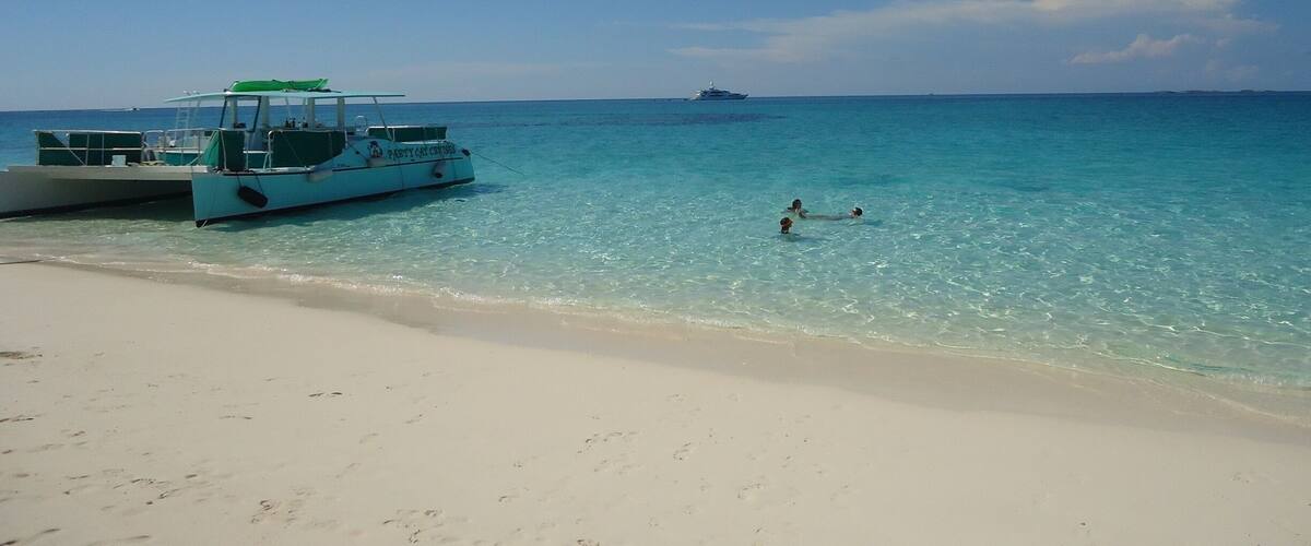 A beach with a boat named "PABIT CHO" and a distant ship.