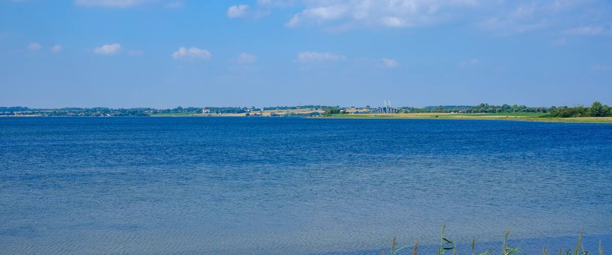 A calm river with a distant bridge and a clear blue sky.