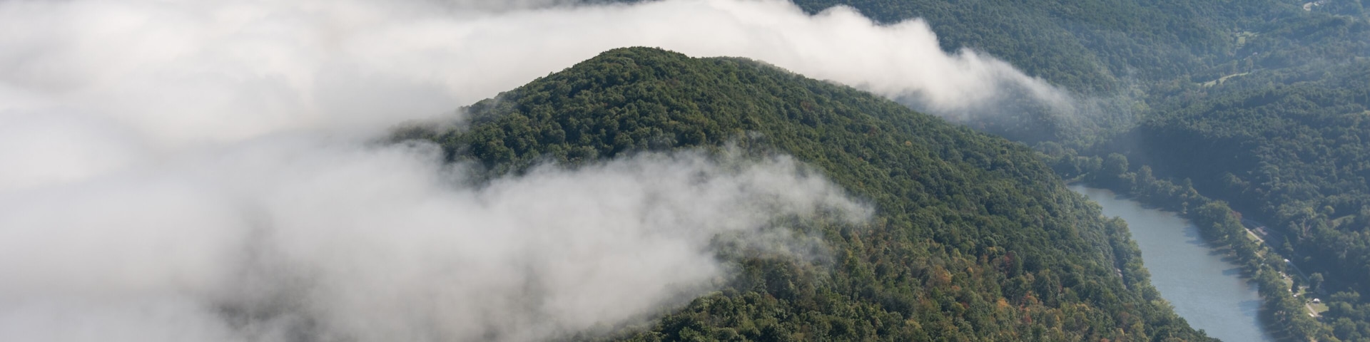 Un paysage montagneux, avec de vastes forêts et une rivière qui serpente à travers les vallées.