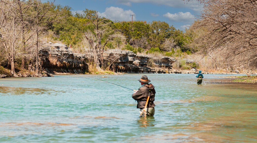 Two anglers fly fishing for trout in the Guadalupe River 5 miles below Canyon Lake Dam facing limestone outcrop in the winter sports paradise of Central Texas, USA.