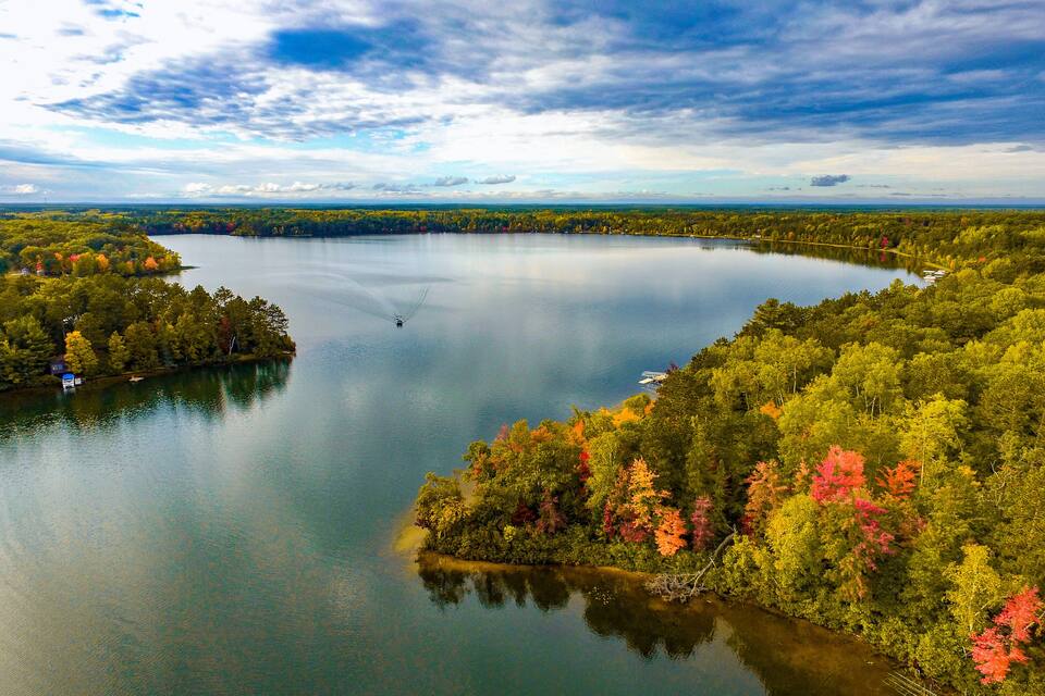 A large lake surrounded by dense forests with autumn foliage.